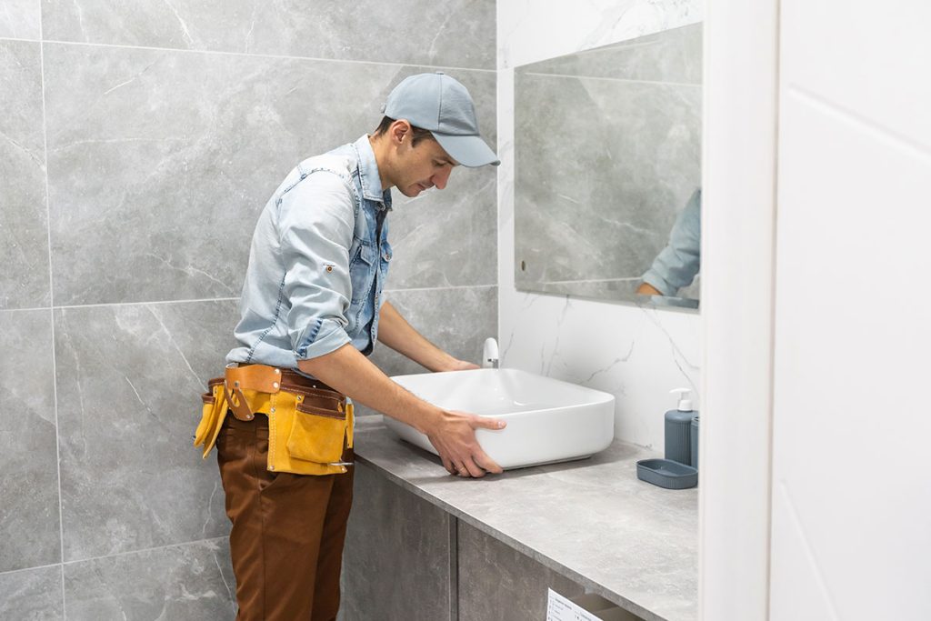 Worker installing bathroom vanity during active washroom renovation